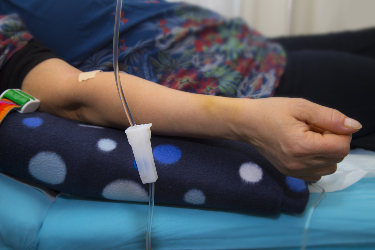 Mature woman with glasses in her 40s having intravenous infusion therapy in the hospital in her hand